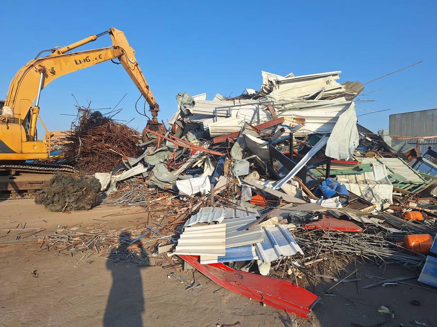 Excavator clearing scrap metal at a site